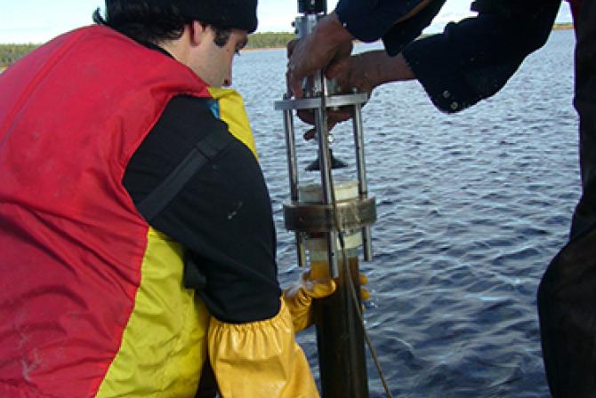 Persons collecting sediment cores from a lake