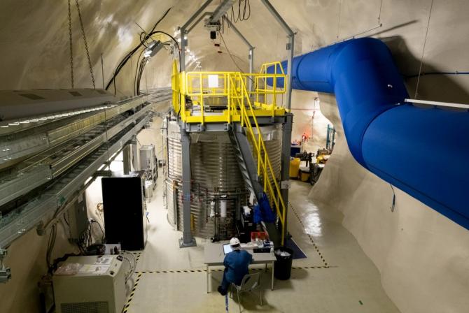 Large underground room where a scientist sits at a table in front of research infrastructure