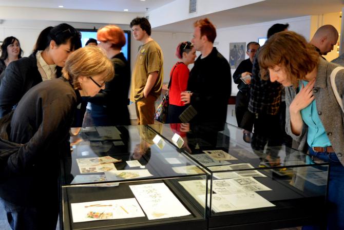 People view drawings and images displayed in glass cases