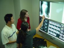Three people examine an X-ray