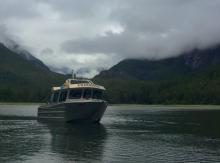 Boat on the water in front of mountains and a cloudy sky