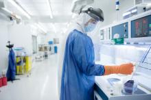 A researcher in full-body personal protective equipment using the cleanroom facility