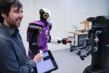 Une personne utilise une tablette électronique pour manipuler deux robots