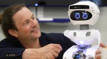 Un chercheur interagit avec un petit robot doté d’intelligence artificielle.