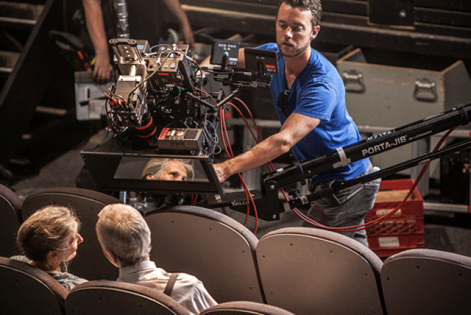 Camera operator films a couple seated in theatre seats