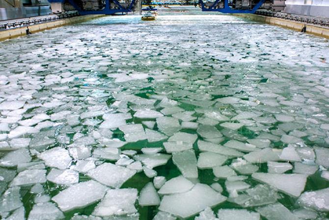 Large rectangular indoor water tank with chunks of ice floating at the surface
