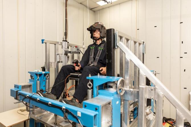 Human test subject wears monitoring equipment while seated on a metal structure