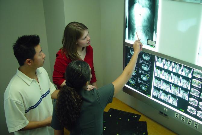 Three people examine an X-ray