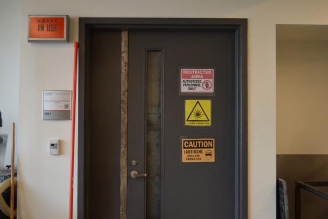 Porte d'entrée d'un labo recouverte de divers autocollants d'avertissement (Zone interdite, Attention, etc.)