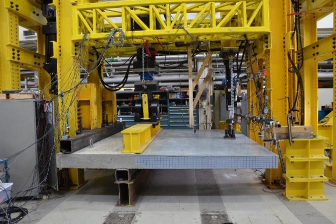 A concrete platform inside a large adjustable load frame with actuators