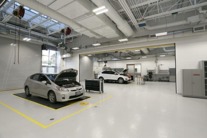 A bright, open garage space with two vehicle bays occupied by vehicles under inspection