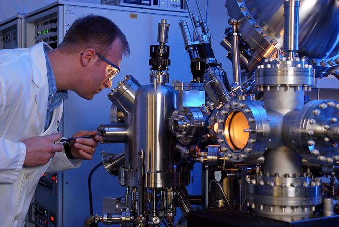 Researcher looking into a large microscope