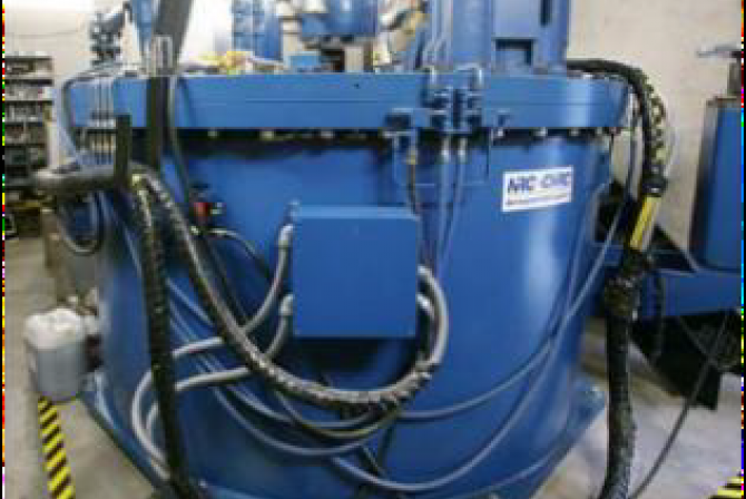 Vue externe d’un imposant banc d’essai cylindrique fermé en métal auquel sont fixés les nombreux gros câbles électriques servant à en chauffer l’intérieur
