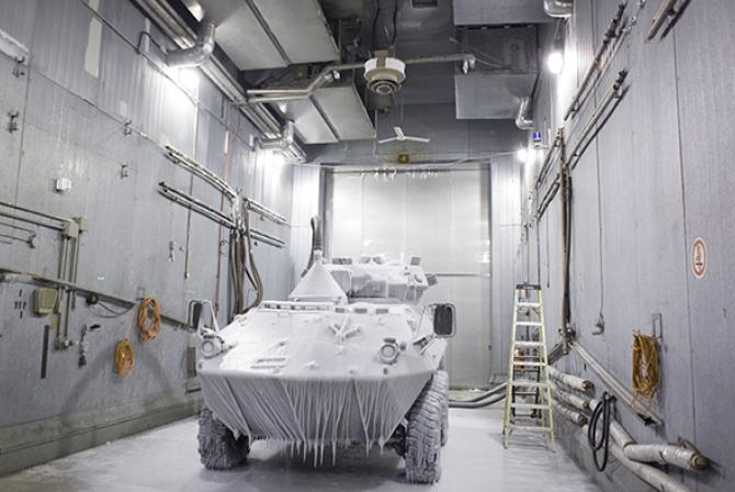 Military vehicle covered in ice in large chamber