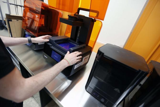 A person manually adjusts a desktop printer.