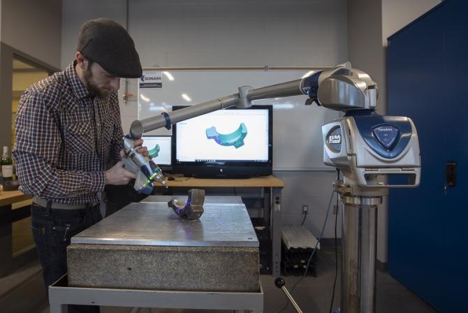 A person uses a robot arm to scan a piece.