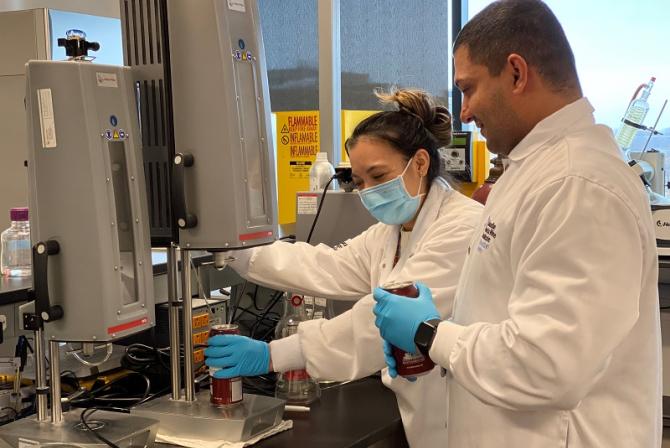 Two people work together to analyze a sample in a can.