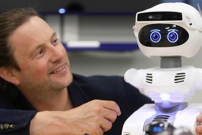 A researcher interacts with a small artificial intelligence robot.
