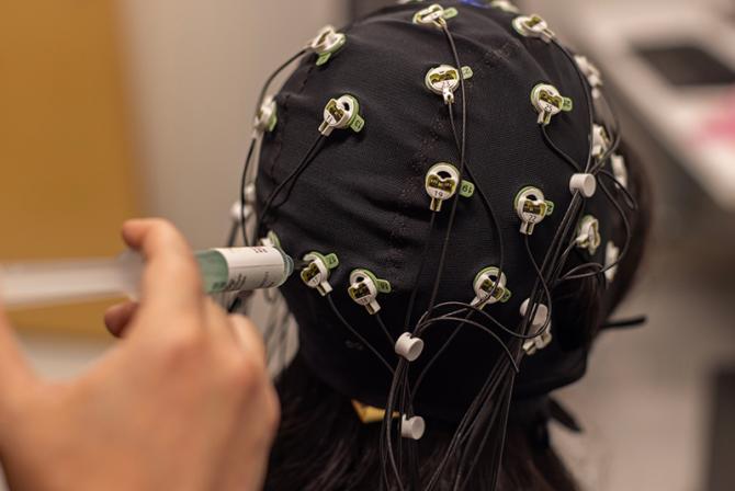A person sets up an EEG cap for testing.