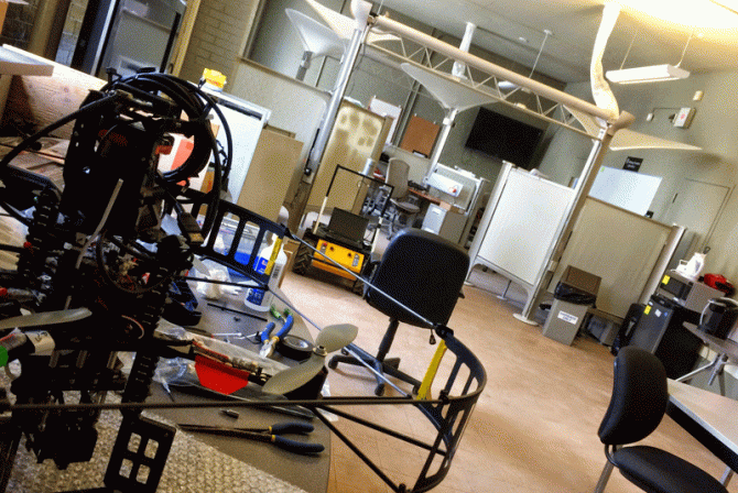 Interior space with workstations and vehicle parts on the floor