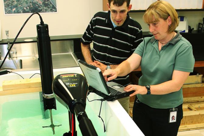 Deux personnes opèrent de l'équipment dans un bassin d'eau en laboratoire