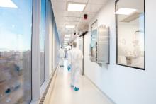 People wearing personal protective equipment walk down a long corridor