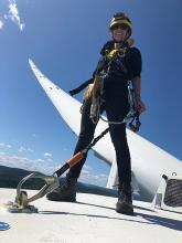 A person stands atop of a wind turbine