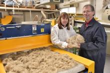 Two researchers standing next to the cleaning unit hold purified straw-fibres.