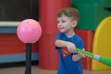 Un enfant s'enligne à frapper un ballon posé sur un support.